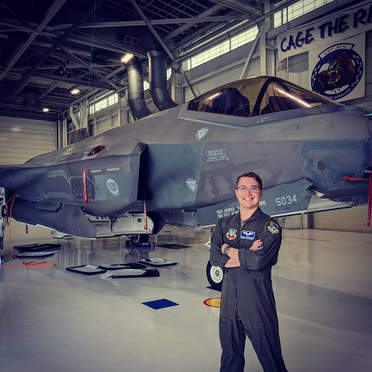 Scott Seidenberger in flight suit positioned near an F-35 aircraft inside a hangar.